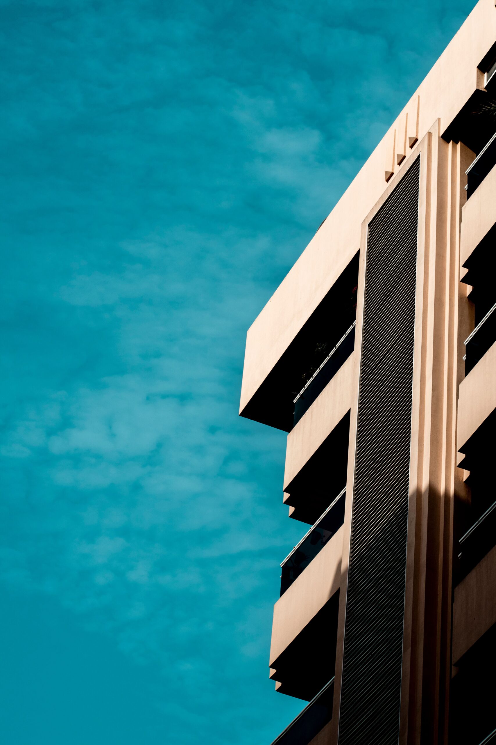 Corner view of a cream mid-rise residential apartment building against a clear blue sky in Dubai