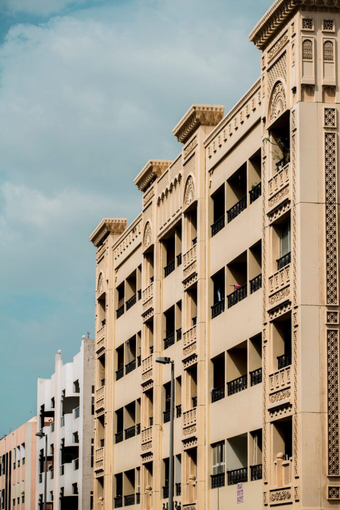Sandstone Arabian-style apartment building with arched balconies and decorative lattice screens in Dubai's Old Town