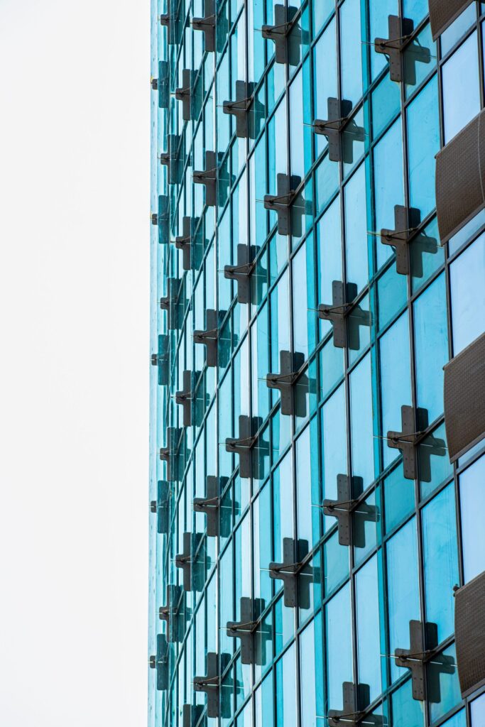 Blue-green glass curtain-wall skyscraper facade with cross-shaped structural mullions in Dubai, representative of Ramada Residences by Wyndham's contemporary residential architecture in Healthcare City Phase 2, Al Jaddaf