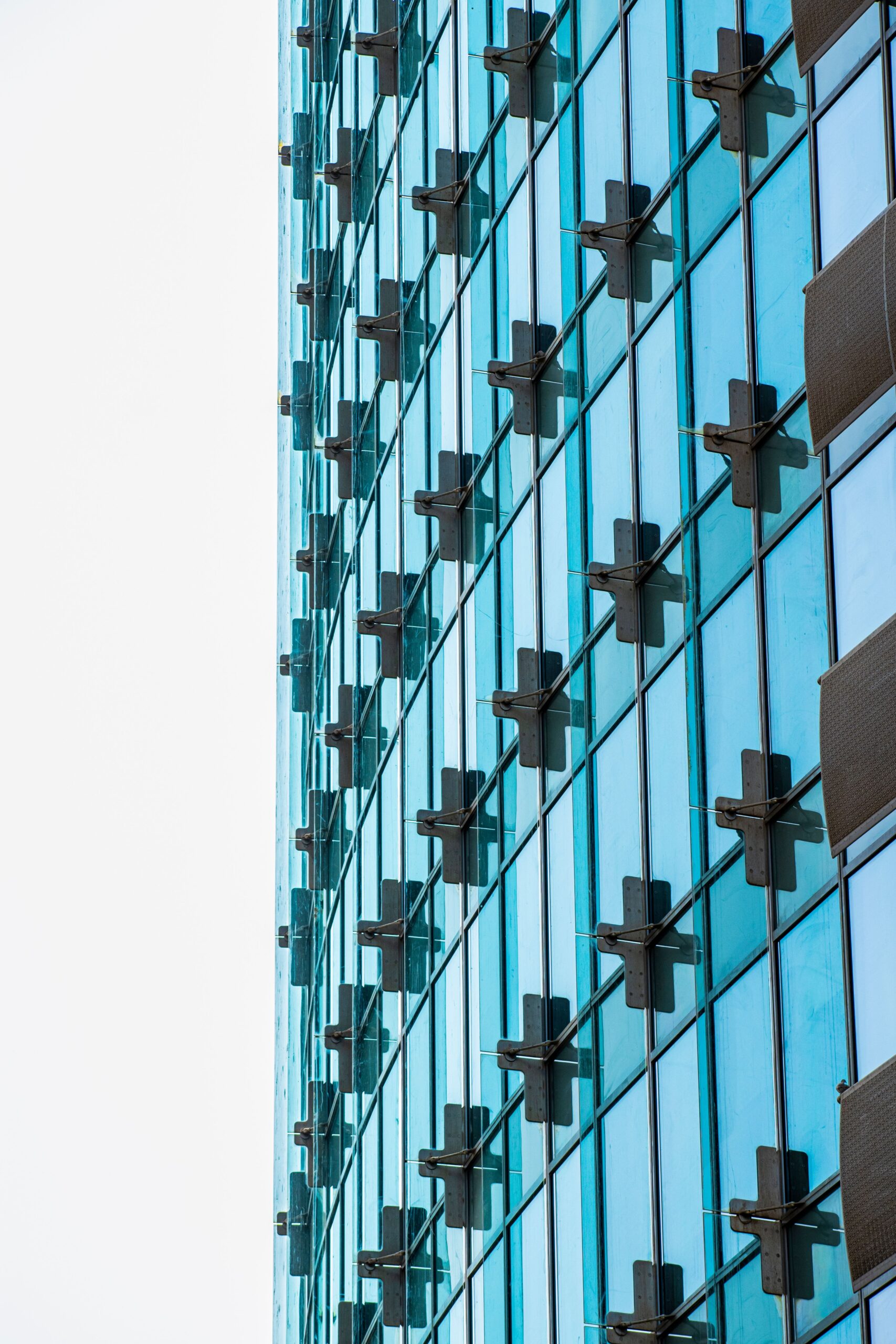 Blue-green glass curtain-wall skyscraper facade with cross-shaped structural mullions in Dubai, representative of Ramada Residences by Wyndham's contemporary residential architecture in Healthcare City Phase 2, Al Jaddaf