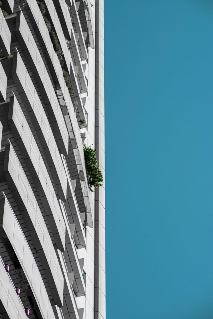 Upward view of a modern Dubai residential building facade with balconies against a clear blue sky, representative of the Arjan area around Divine Living
