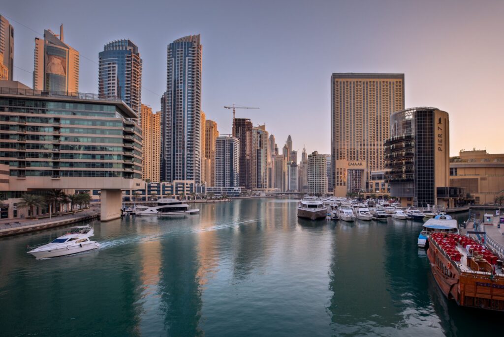 Dubai Marina canal with a yacht and residential towers at dusk