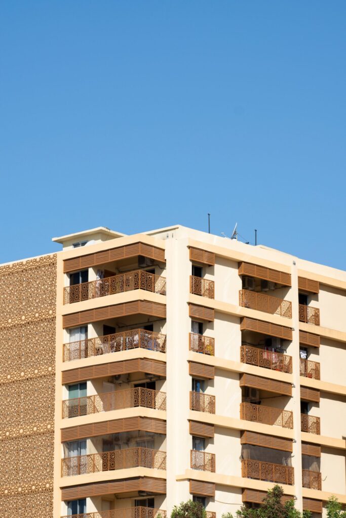 Sunlit mid-rise apartment building with geometric balcony screens in Dubai