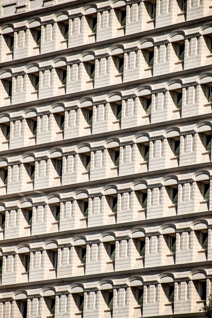 Repeating pattern of cream apartment building window bays with arched balcony canopies against a blue sky in Dubai