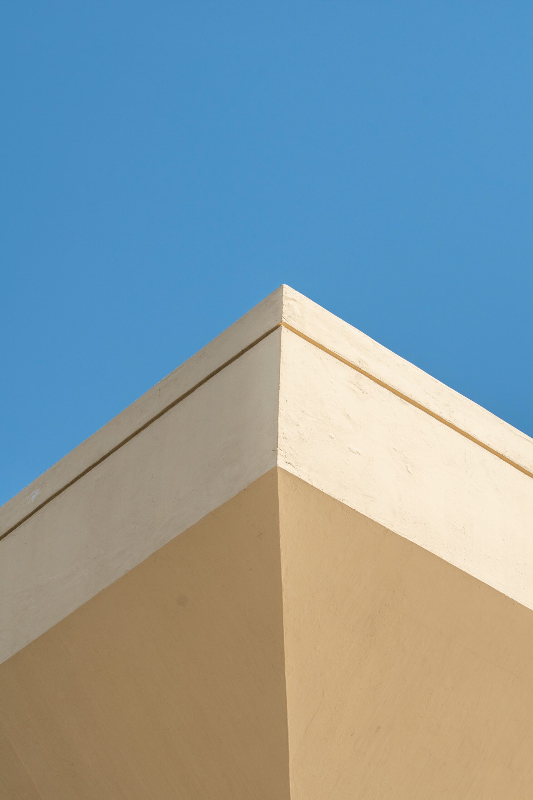Minimalist cream and beige building corner detail against a clear blue sky in Dubai