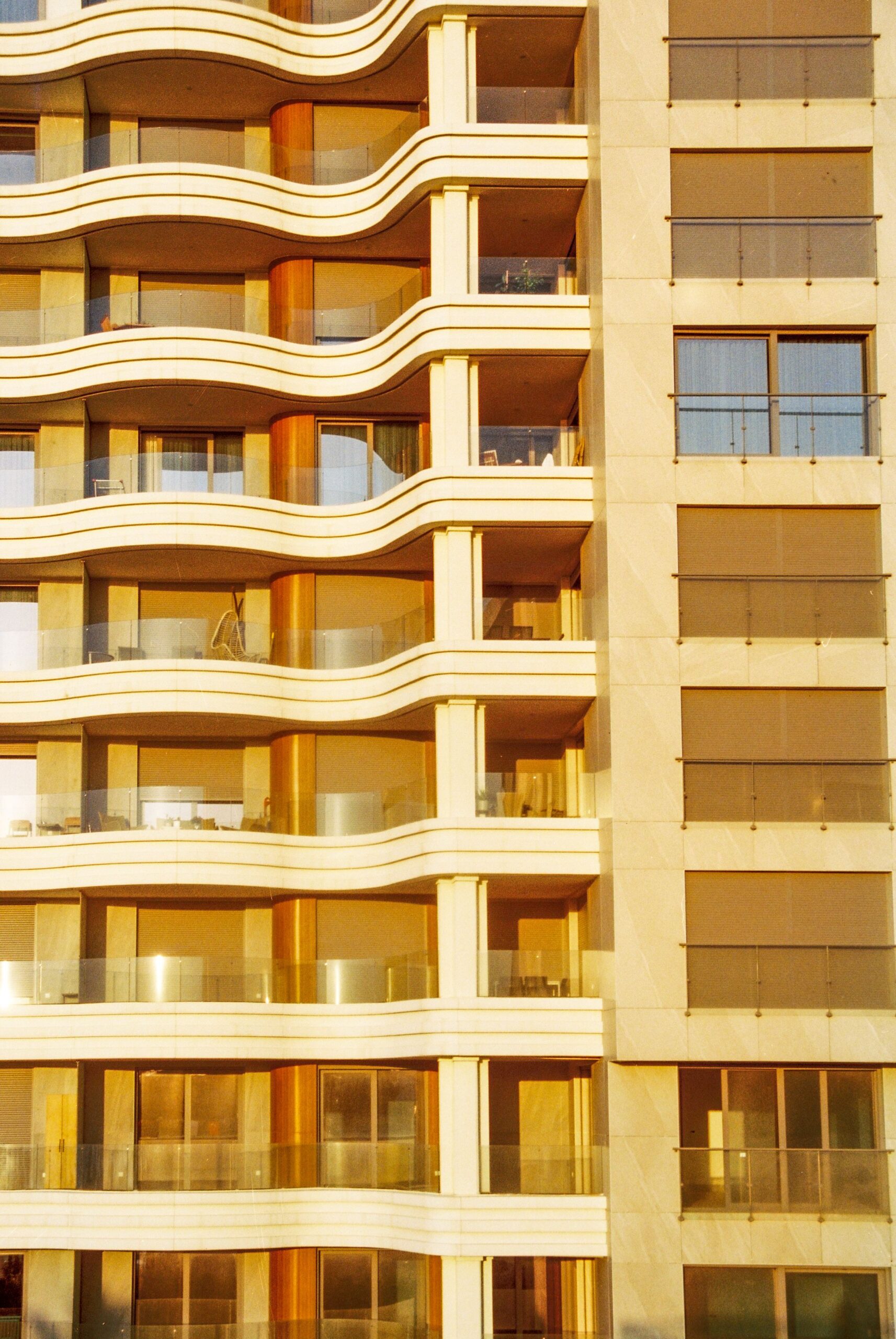Golden hour view of a modern residential building facade with curved balconies in Dubai