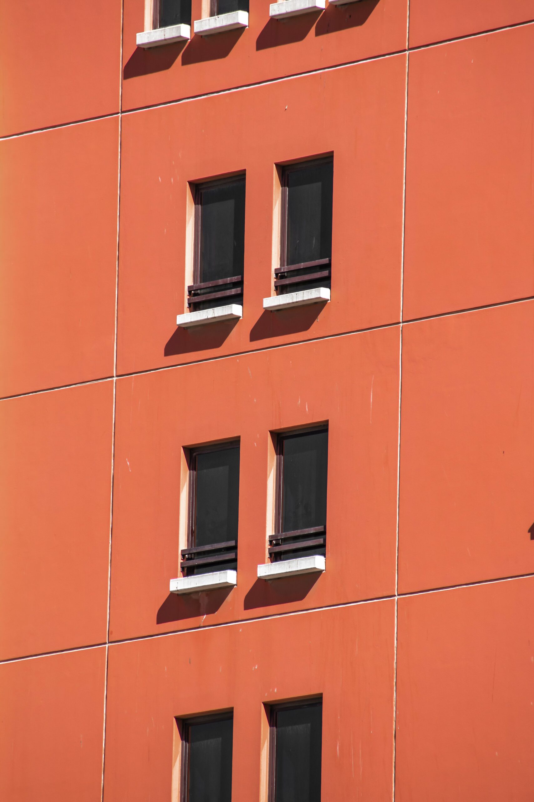 Sunlit terracotta apartment building facade with shuttered windows in Dubai