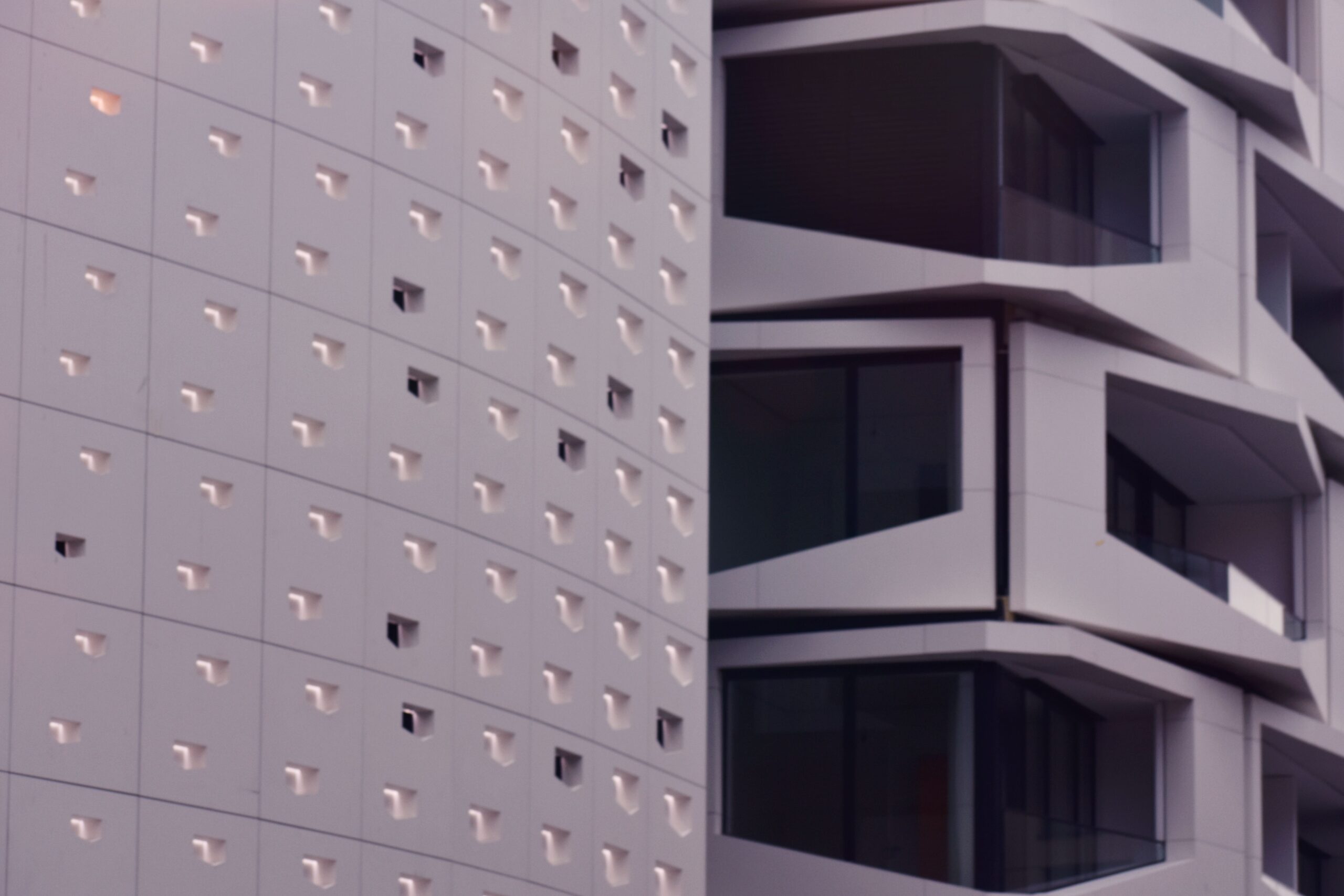 Modern high-rise building with an angular, sculptural white facade, similar in style to The Community, JVT