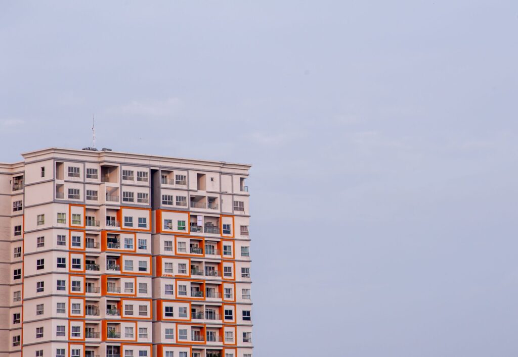 Upward view of a modern high-rise apartment building with an orange and white facade in Dubai