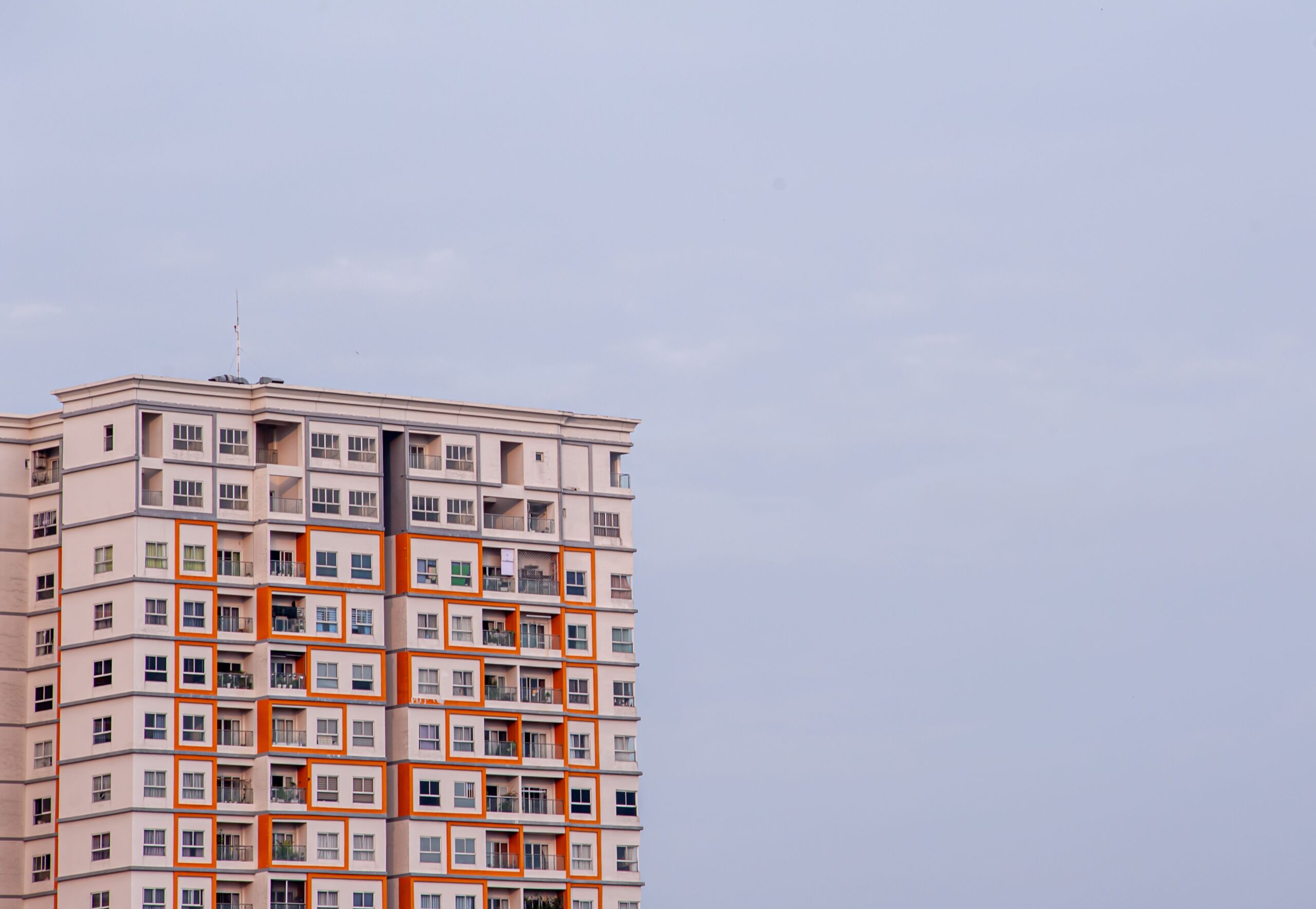 Upward view of a modern high-rise apartment building with an orange and white facade in Dubai