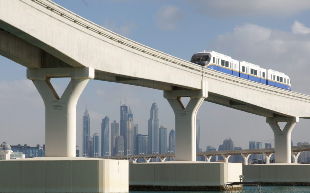 The Palm Jumeirah Monorail crossing a raised track with the Dubai Marina skyline visible in the background