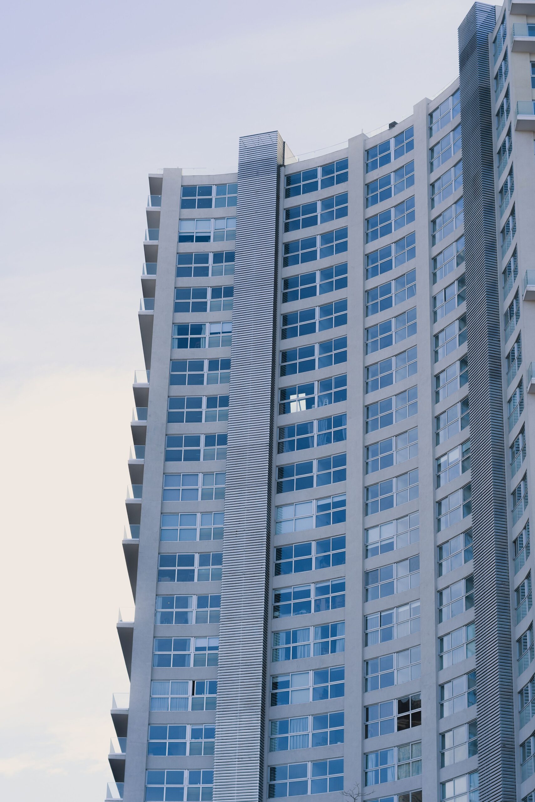 Tall curved-corner Dubai apartment tower with blue glass windows, representative of Sondos Orchid in DubaiLand Residence Complex, Dubai