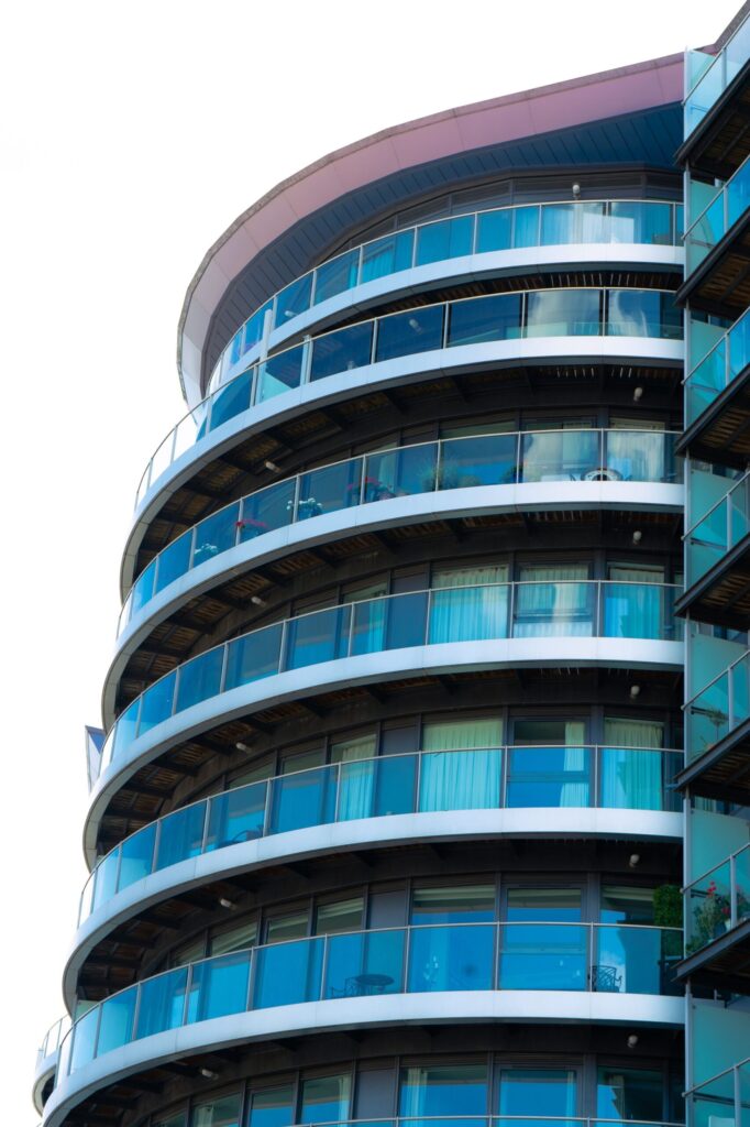 Curved modern apartment building with glass balconies, representative of UniEstate Millenium Tower in Dubai Silicon Oasis, Dubai
