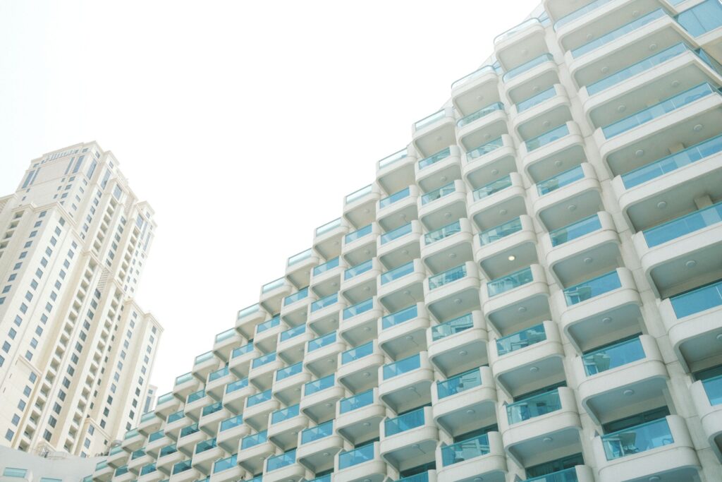 Upward view of a stepped modern residential tower with rows of balconies against a bright sky, Dubai