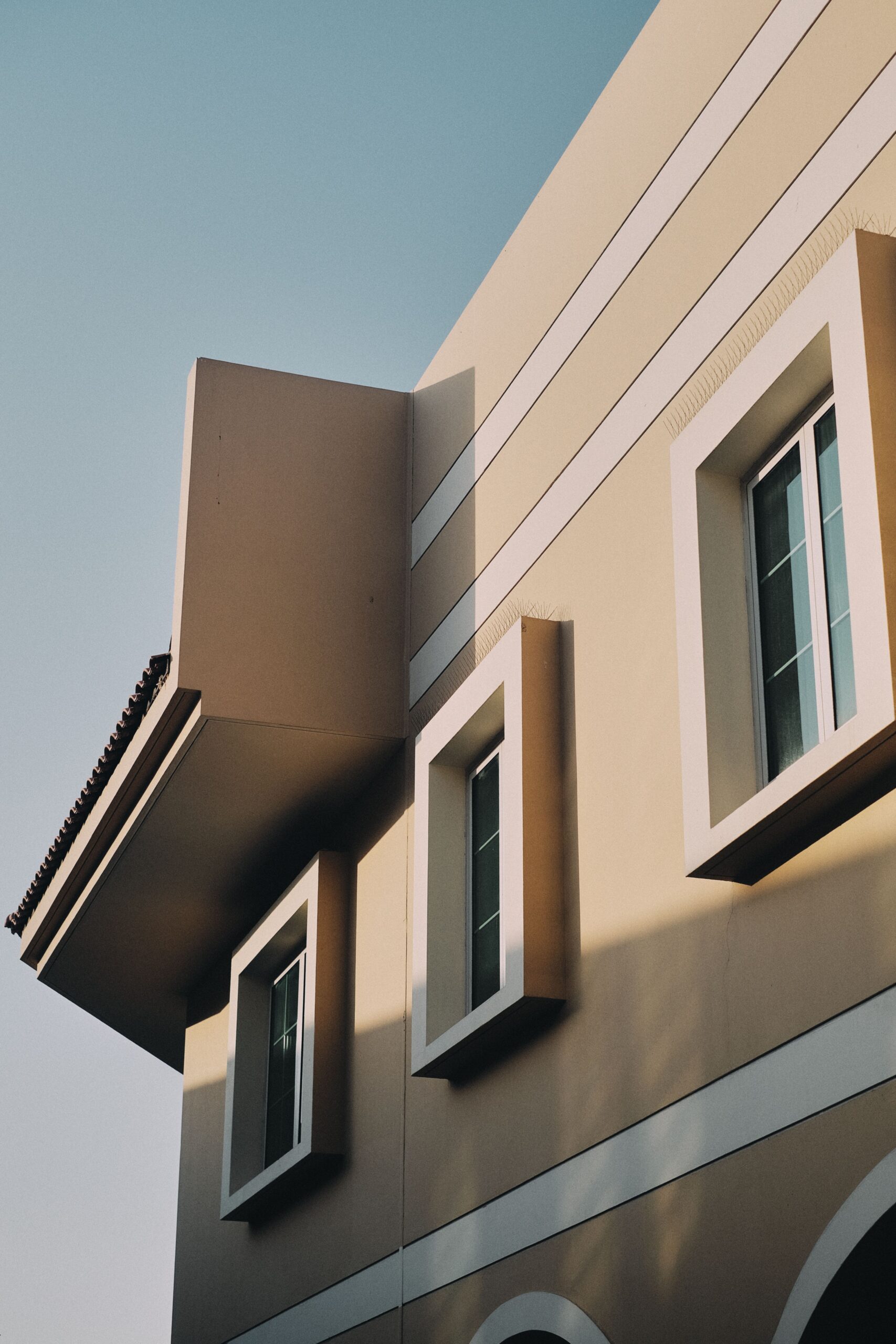 Clean modern beige apartment building corner with sharp window surrounds against a clear blue sky in Dubai