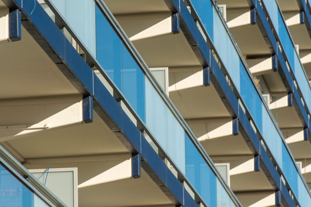 Close-up of geometric blue-glass balconies on a modern Dubai residential tower facade near The Manhattan Tower, JVC