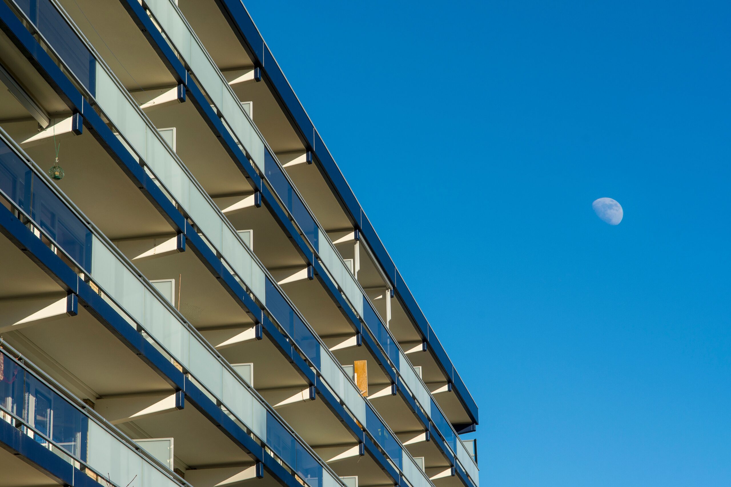 Modern apartment building facade with navy-trimmed balconies under a clear blue sky, similar in style to Bluebell Residence, JVC