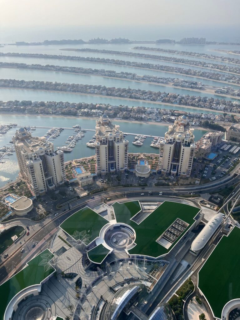 Aerial view of curved waterfront towers around a private yacht marina at the tip of Palm Jumeirah, Dubai