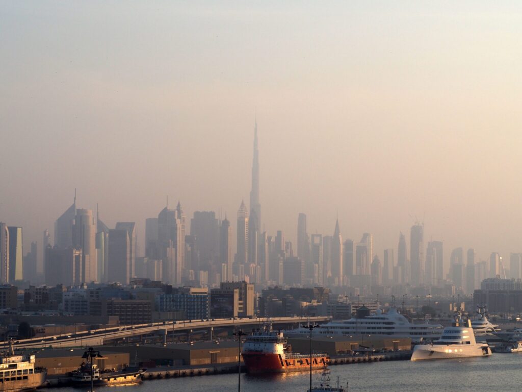 Hazy Dubai skyline seen across a harbour at sunrise