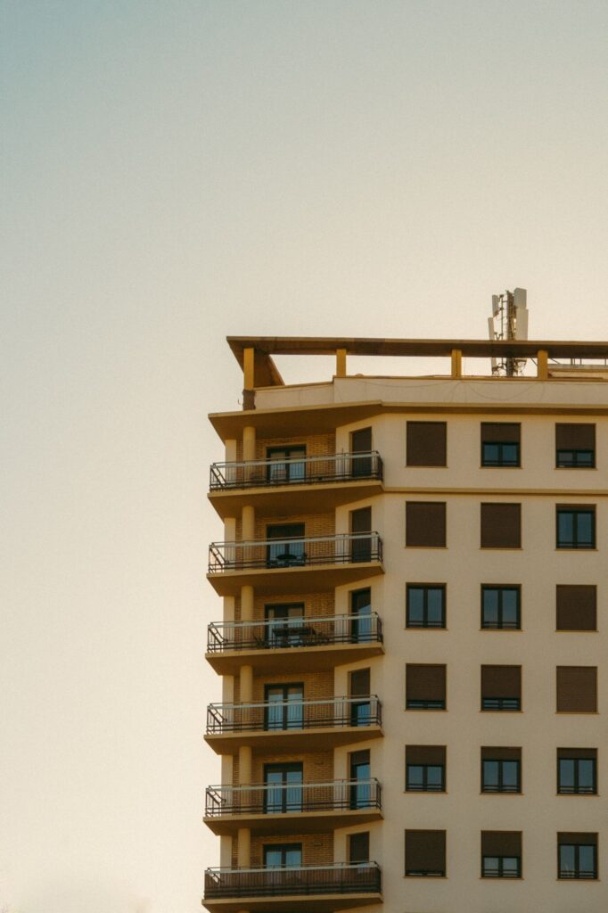 Warm sunset-toned modern apartment building corner with dark balcony railings, representative of Binghatti Sapphires in Dubai Silicon Oasis, Dubai