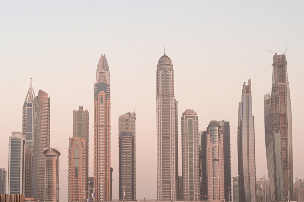 Tall Dubai skyscrapers rising through a soft pink morning haze