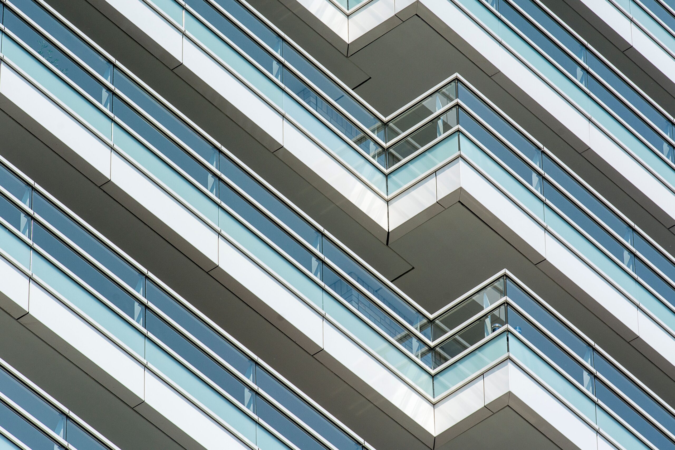 Close-up of angular chevron-patterned glass balconies on a modern high-rise facade, representative of contemporary Dubai apartment architecture