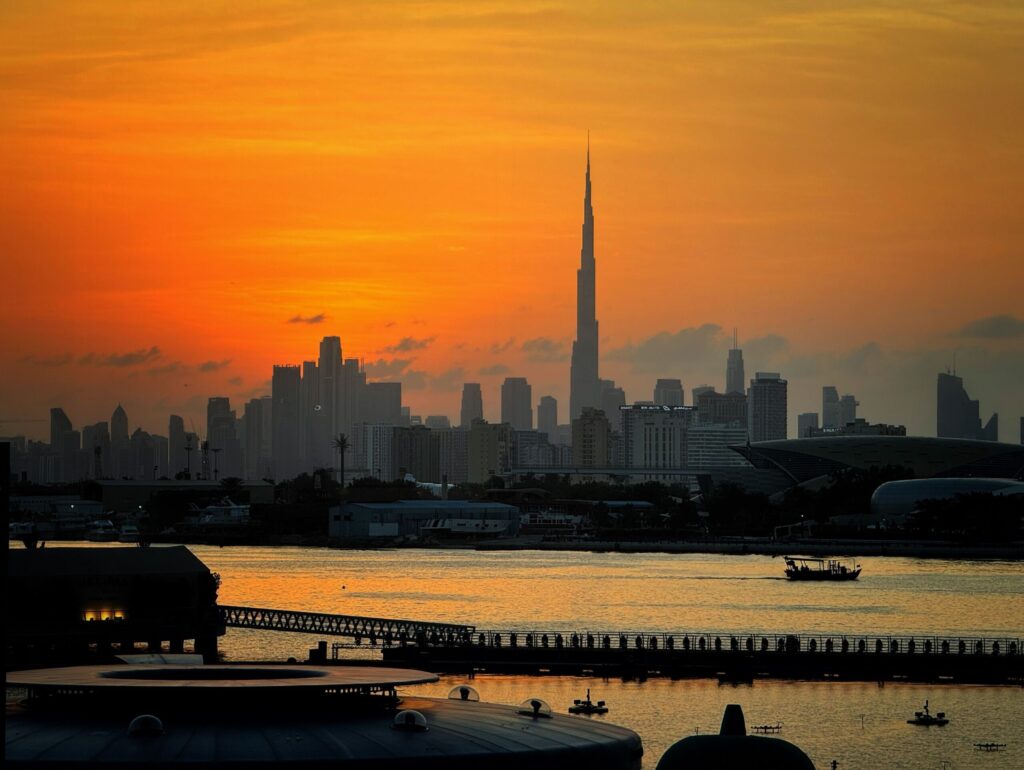 Dubai skyline silhouette with Burj Khalifa at dramatic orange sunset over water