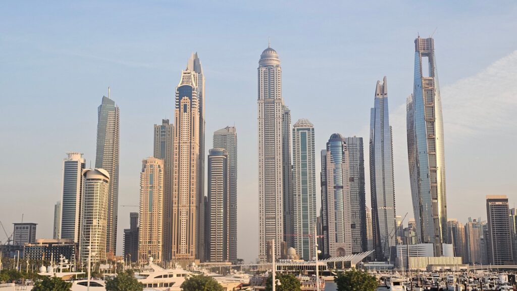 Panoramic view of a modern Dubai waterfront skyline with high-rise towers and a marina under a clear blue sky