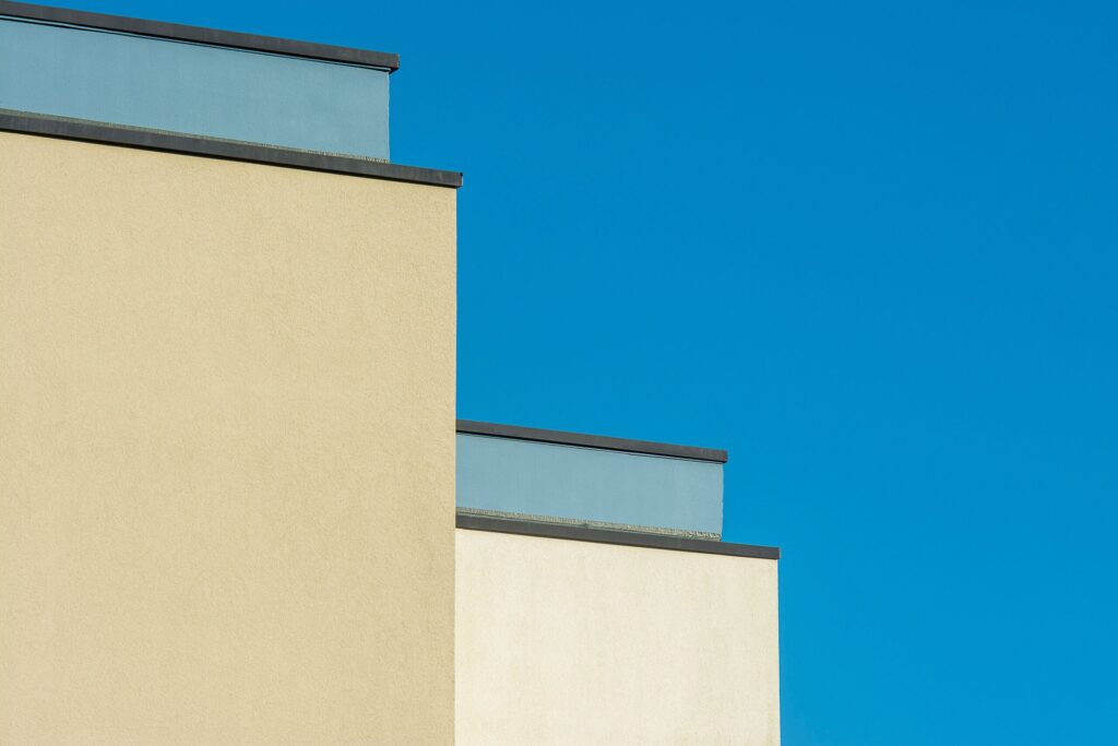 Minimalist cream and tan building facades stepping in tiers against a clear blue sky in Dubai