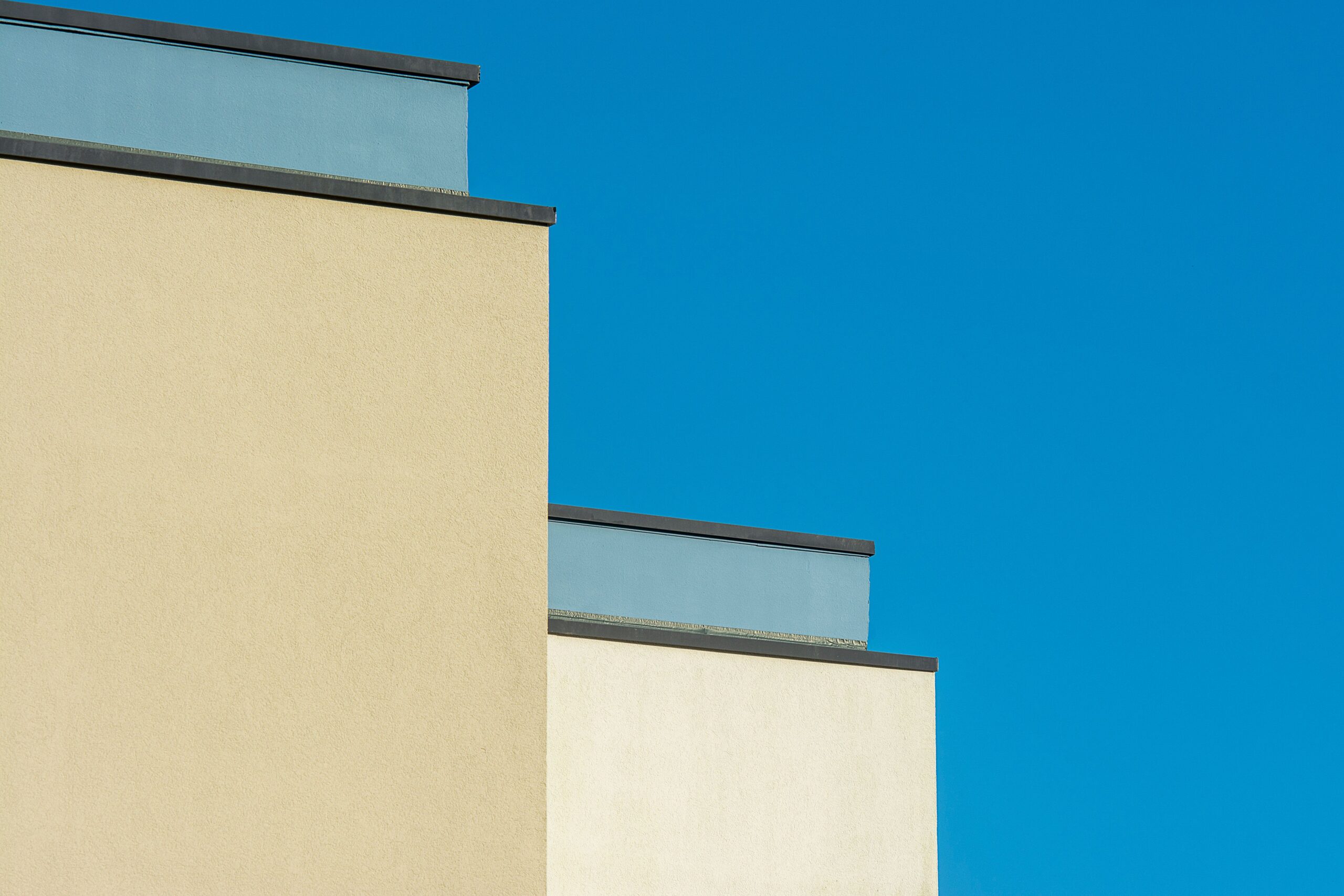 Minimalist cream and tan building facades stepping in tiers against a clear blue sky in Dubai