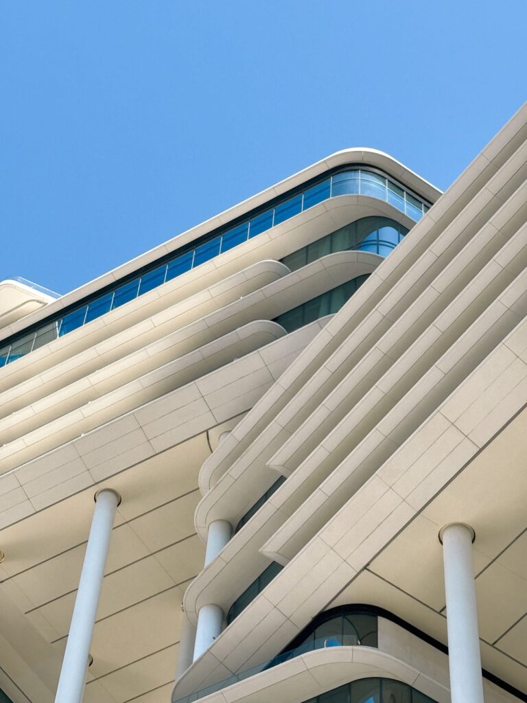 White Dubai apartment building with curved ribbon-style balconies against a clear blue sky