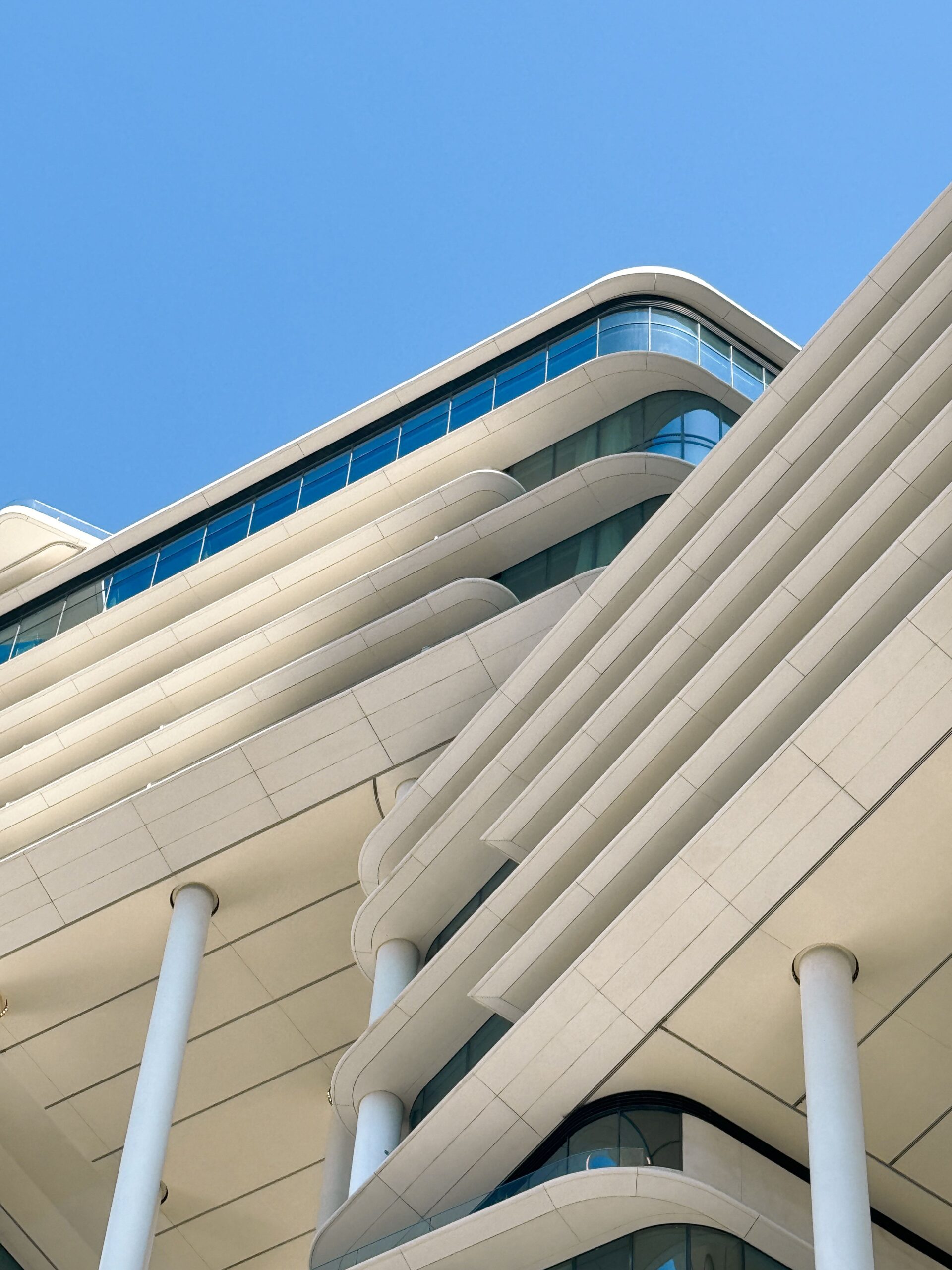 White Dubai apartment building with curved ribbon-style balconies against a clear blue sky