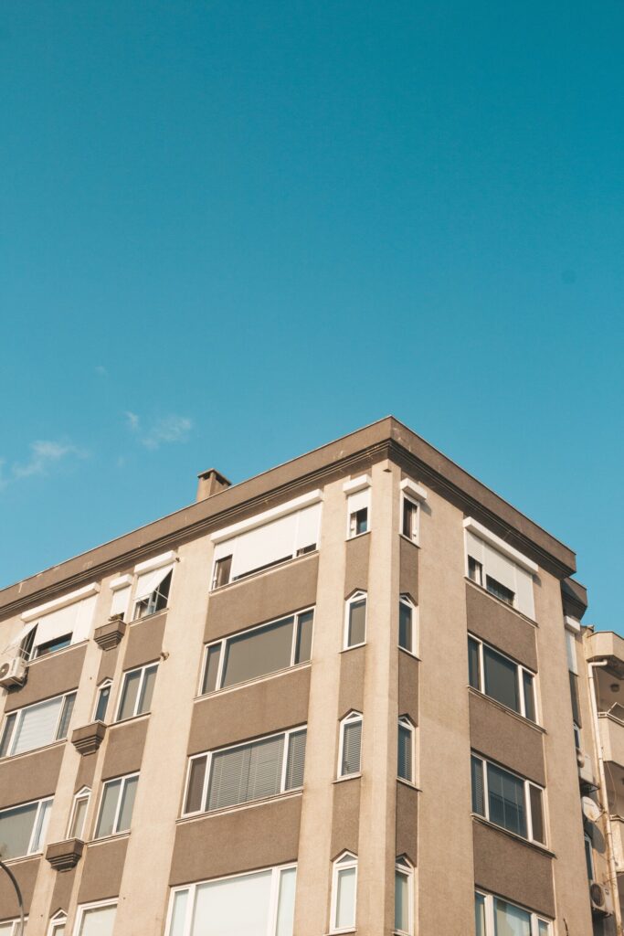 Corner view of a beige mid-rise apartment building against a clear blue sky in Dubai