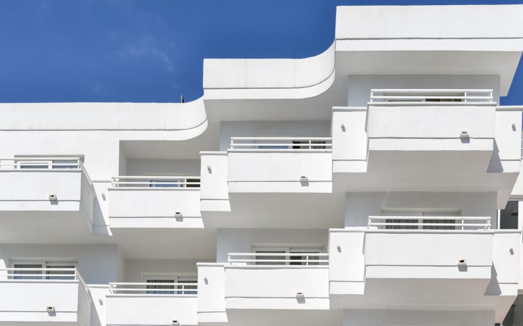 Clean white minimalist Dubai apartment building facade with curved balconies against a blue sky