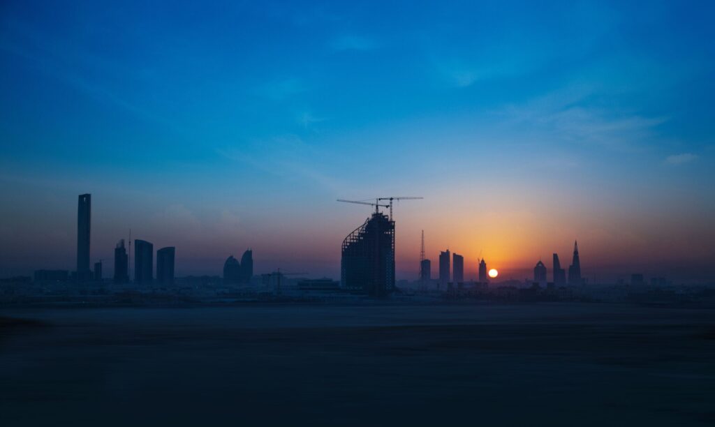 Distant Dubai skyline silhouette at dusk with one tower under construction beside a crane, evocative of Skyvue Solair's still-developing Sobha Hartland II setting