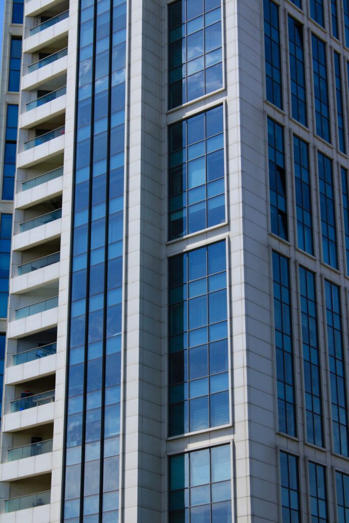 Close-up view of a modern Dubai residential tower with blue glass panels reflecting the sky, representative of Sondos Rosa in DubaiLand Residence Complex, Dubai