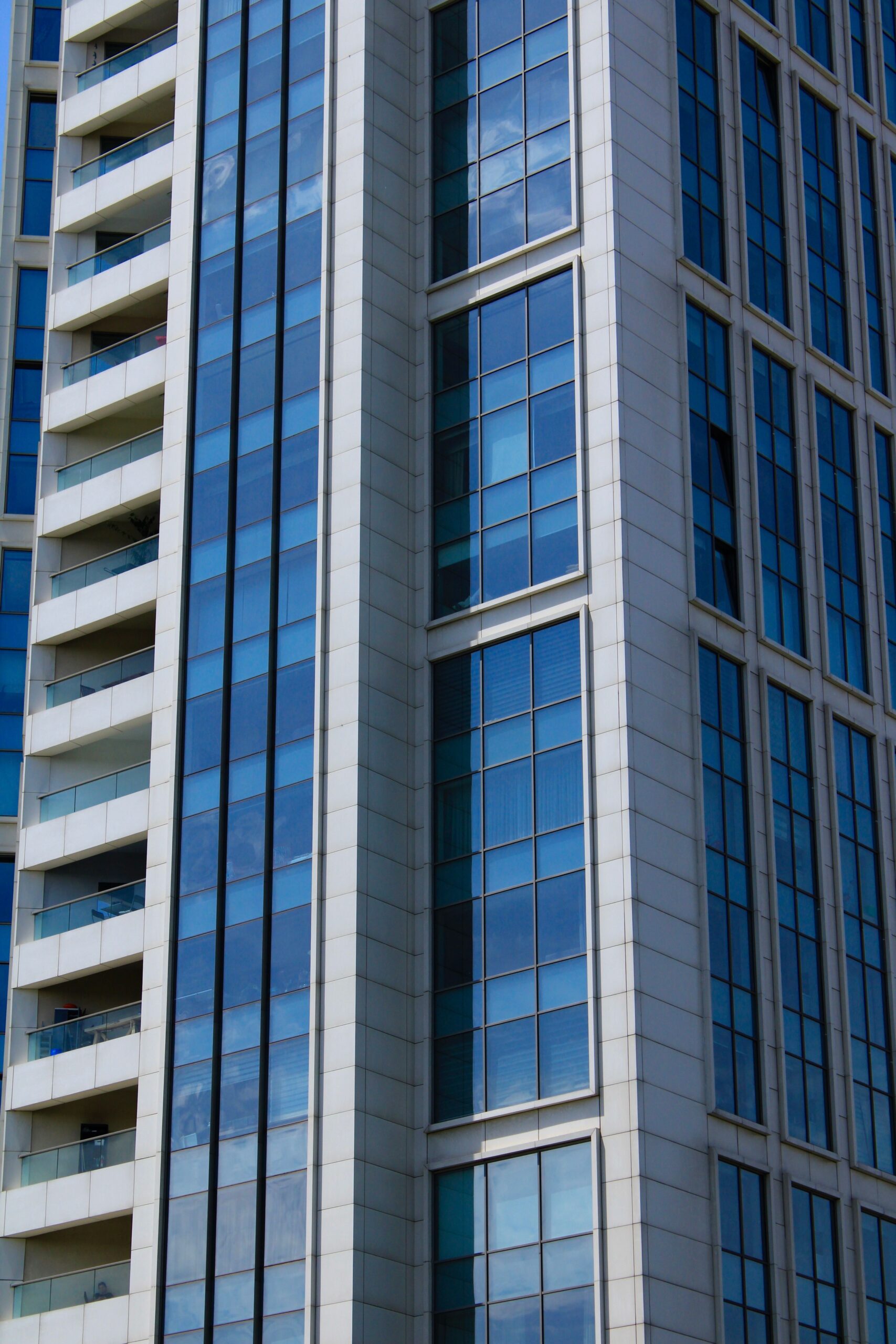 Close-up view of a modern Dubai residential tower with blue glass panels reflecting the sky, representative of Sondos Rosa in DubaiLand Residence Complex, Dubai