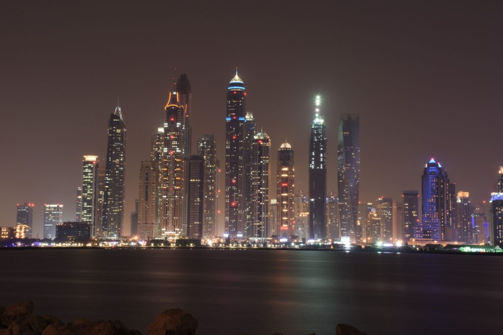 Dubai skyscrapers lit up at night and reflected in still water