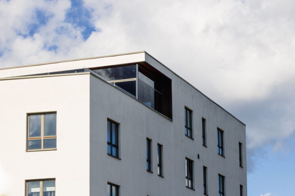 White modern apartment building with a glazed corner terrace under a cloudy sky