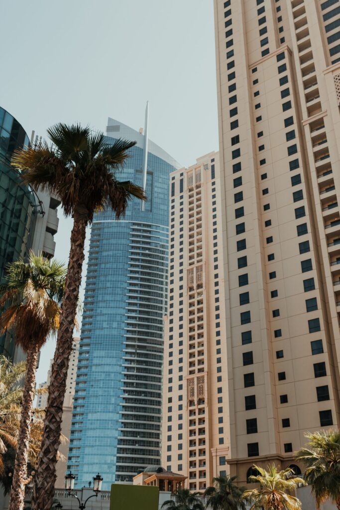 Modern Dubai high-rise apartment towers with palm trees in the foreground under a clear sky
