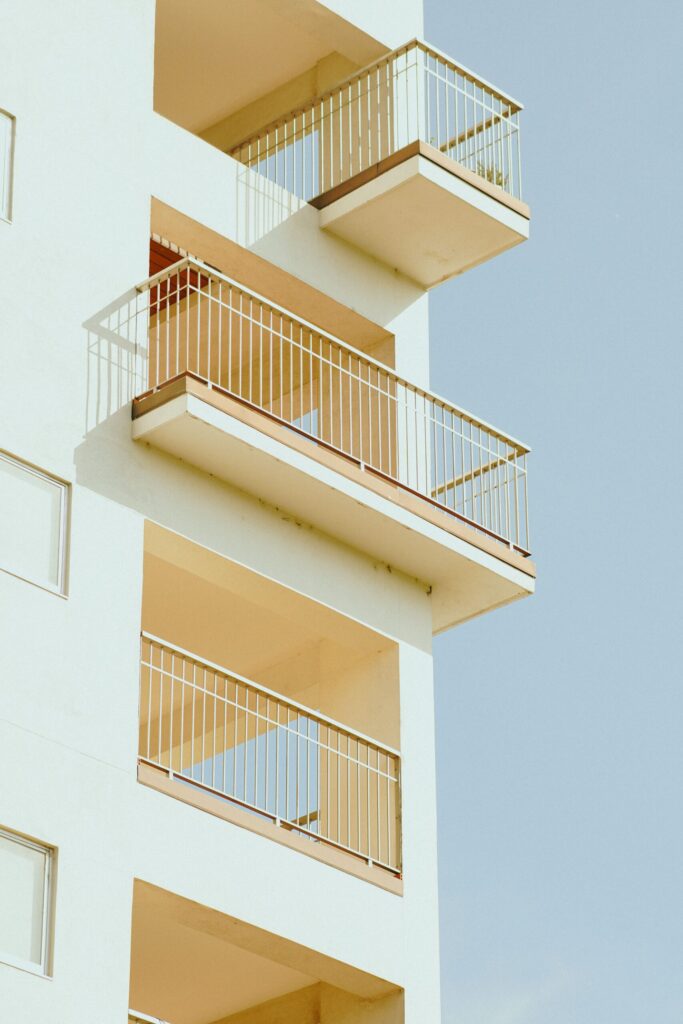 Stylish minimalist high-rise apartment building with stacked balconies against a clear sky in Dubai