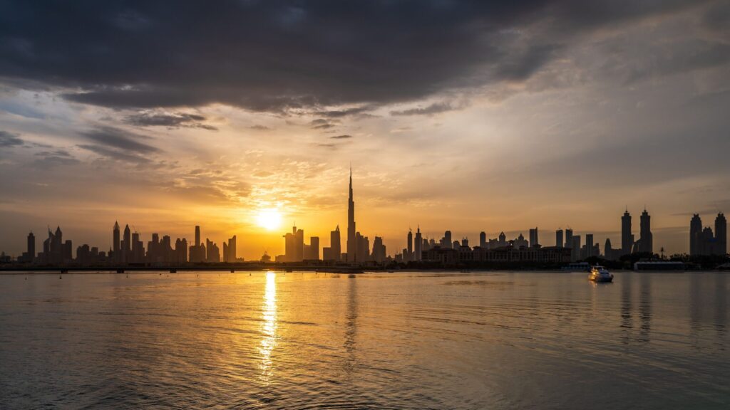 Sun setting over the Dubai skyline and calm water