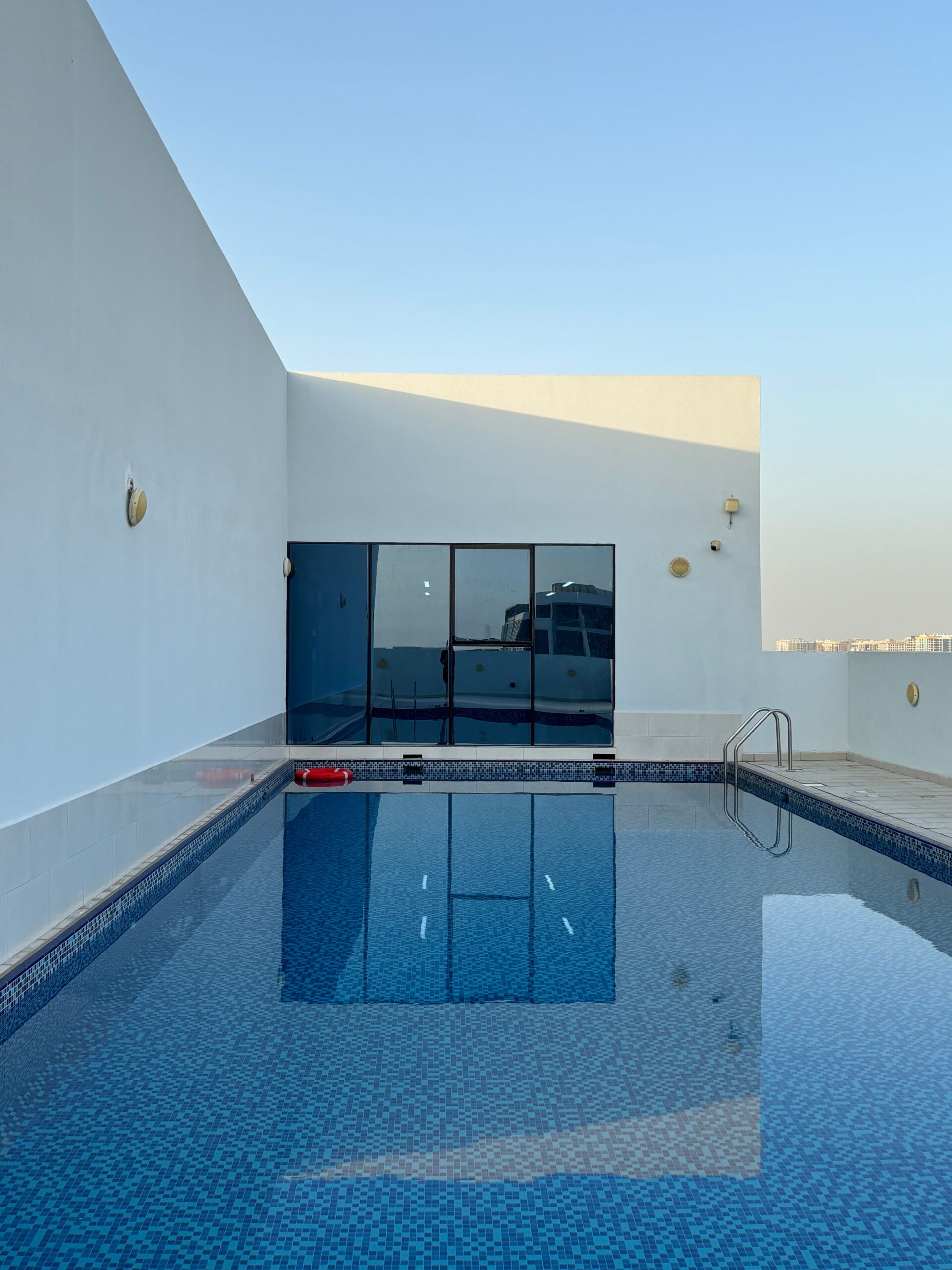 Clean rooftop swimming pool with minimalist white architecture, representative of low-rise residential buildings near Elz Residence by Danube in Arjan, Dubai