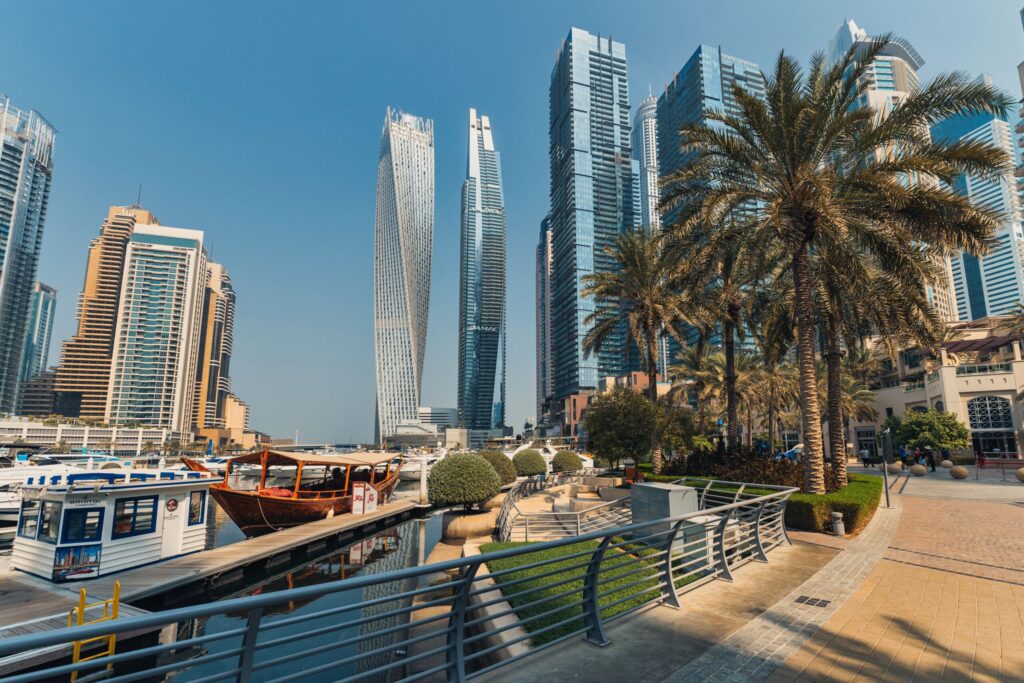Daytime view of Dubai Marina's twisted Cayan Tower and waterfront promenade with palm trees