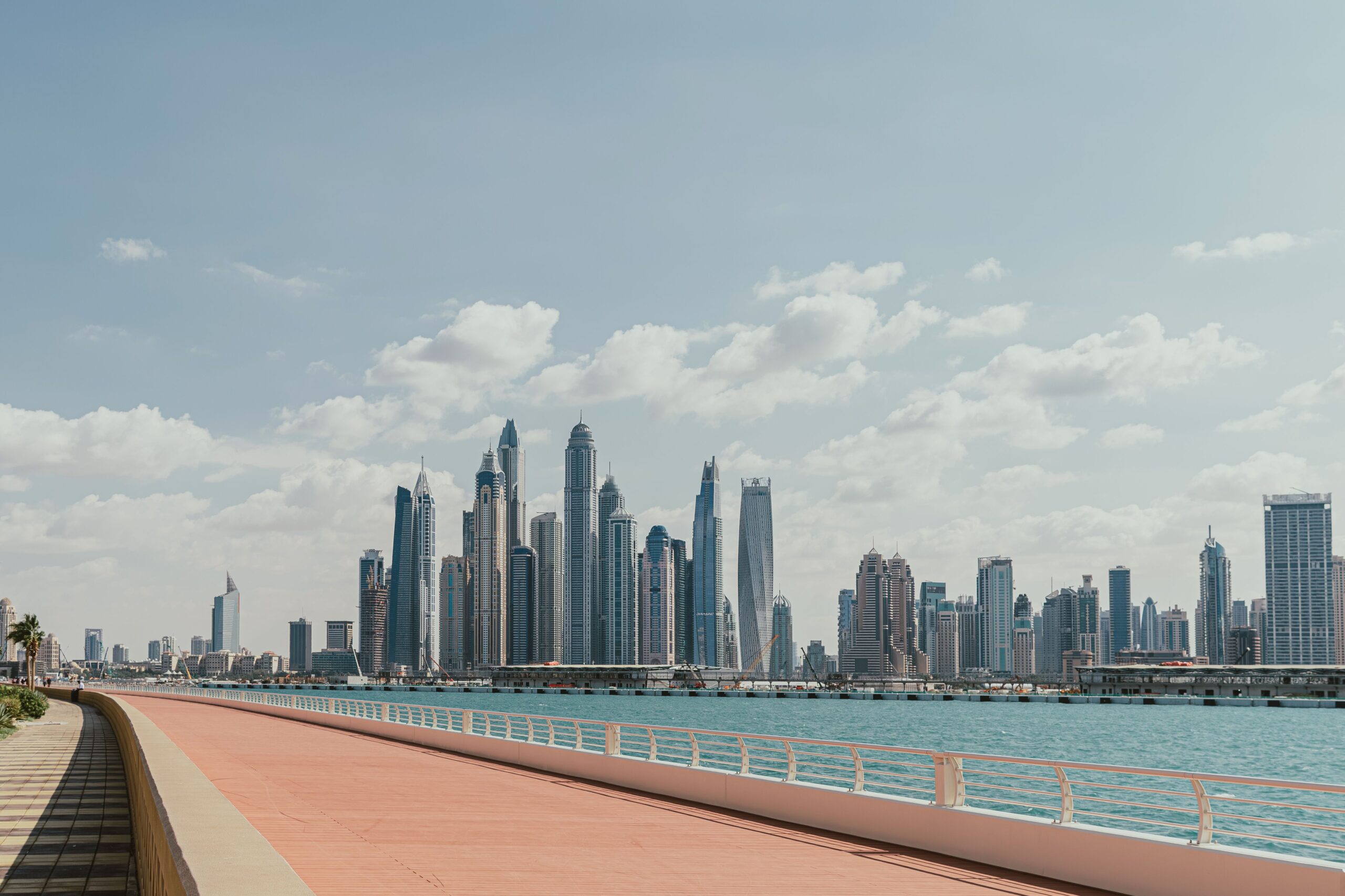Daytime view of the Dubai Marina skyline and waterfront promenade under a clear blue sky