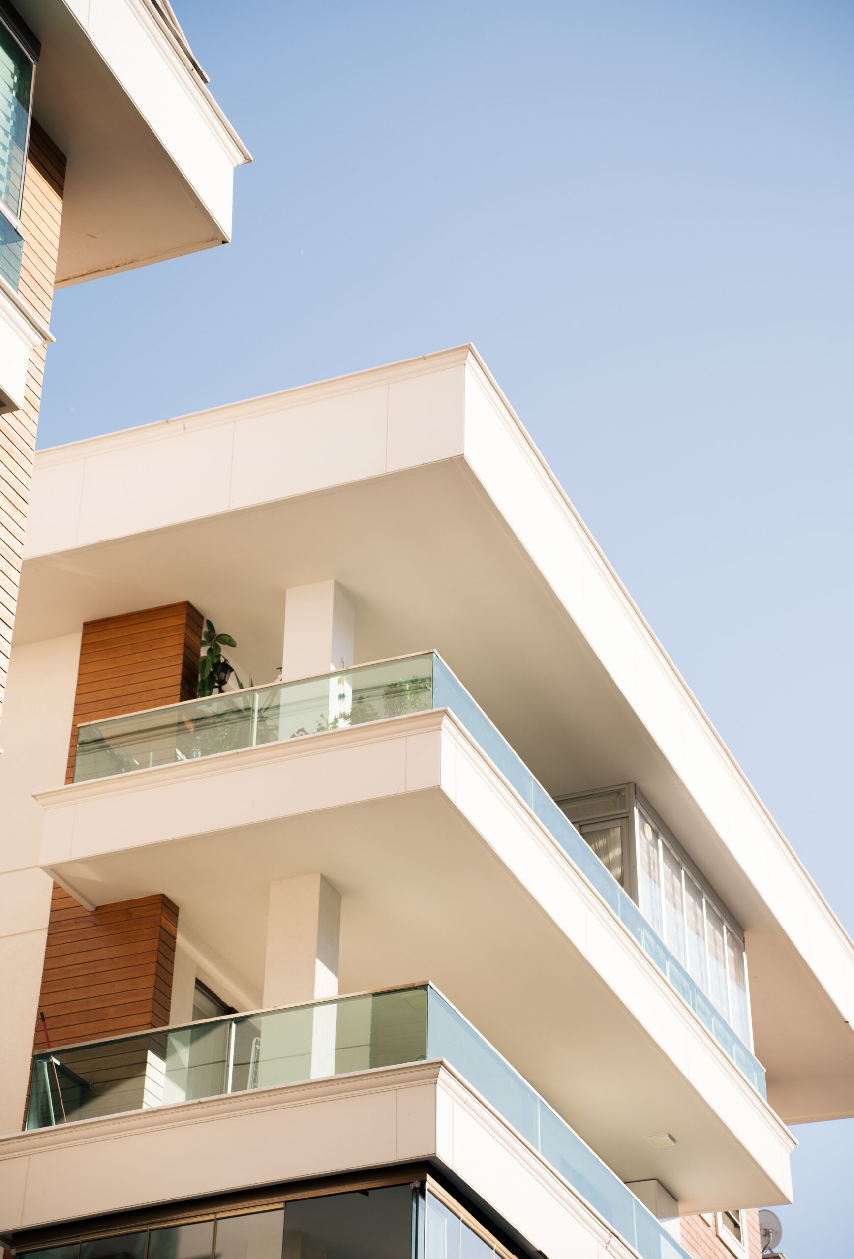 Cream-toned modern apartment building corner with balconies under a clear blue sky, representative of Binghatti Point in Dubai Silicon Oasis, Dubai