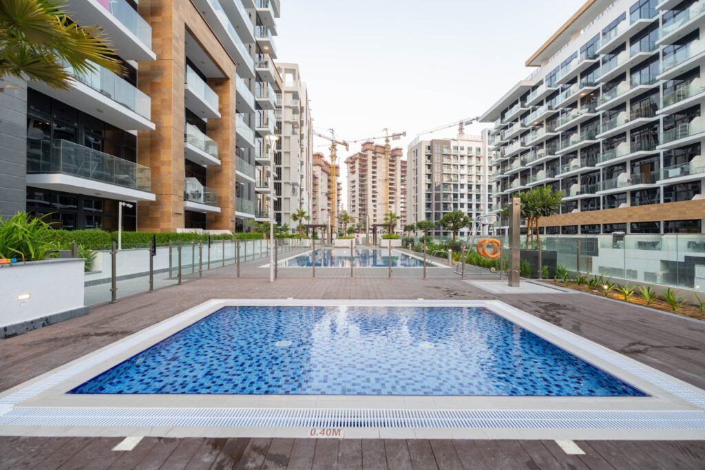 Mid-rise Dubai residential complex with a swimming pool courtyard and construction cranes visible in the background, similar to MAG 890 in MAG City, MBR City