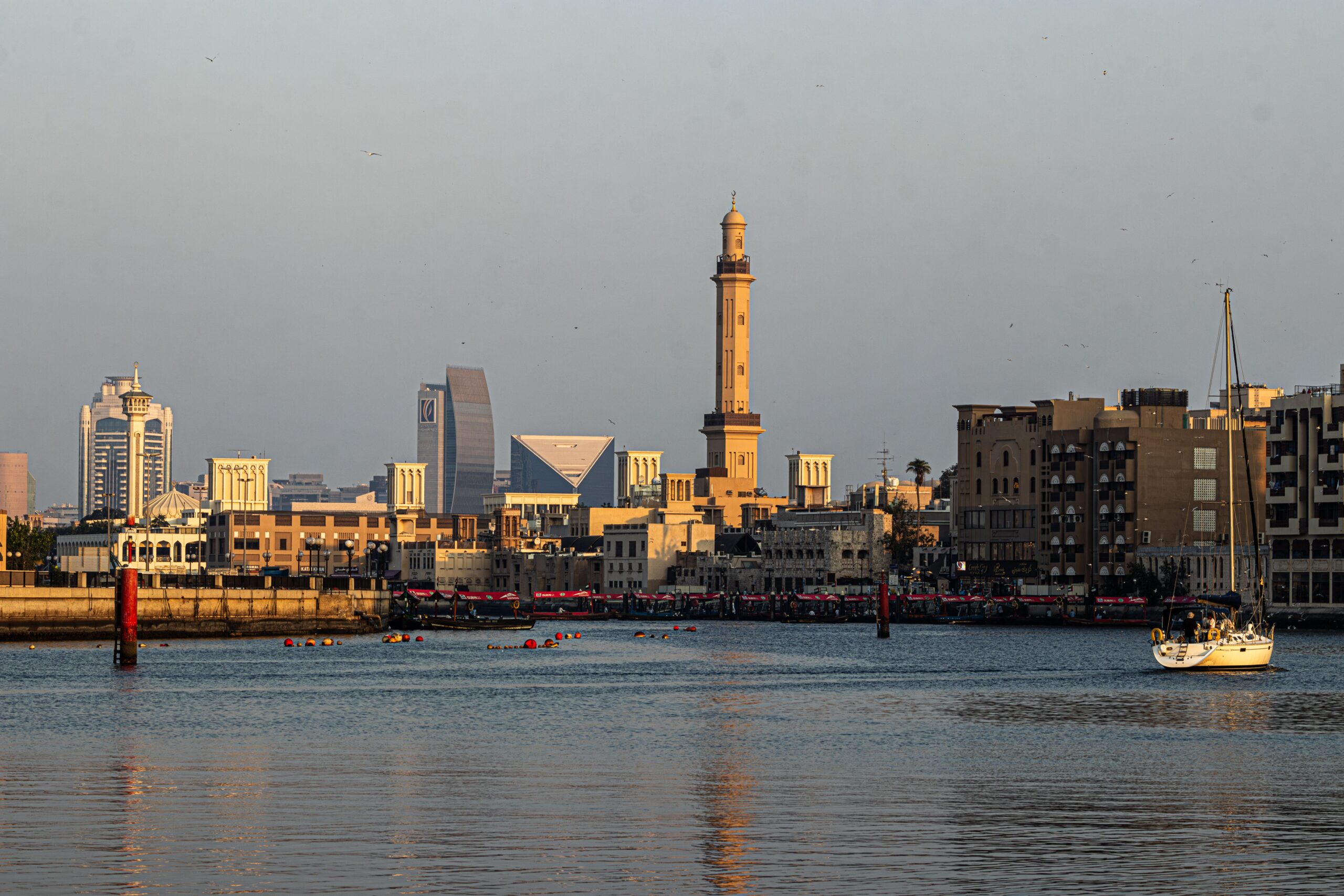 Dubai Creek waterfront skyline at golden hour with a traditional minaret and modern towers, near O Ten in Healthcare City, Al Jaddaf