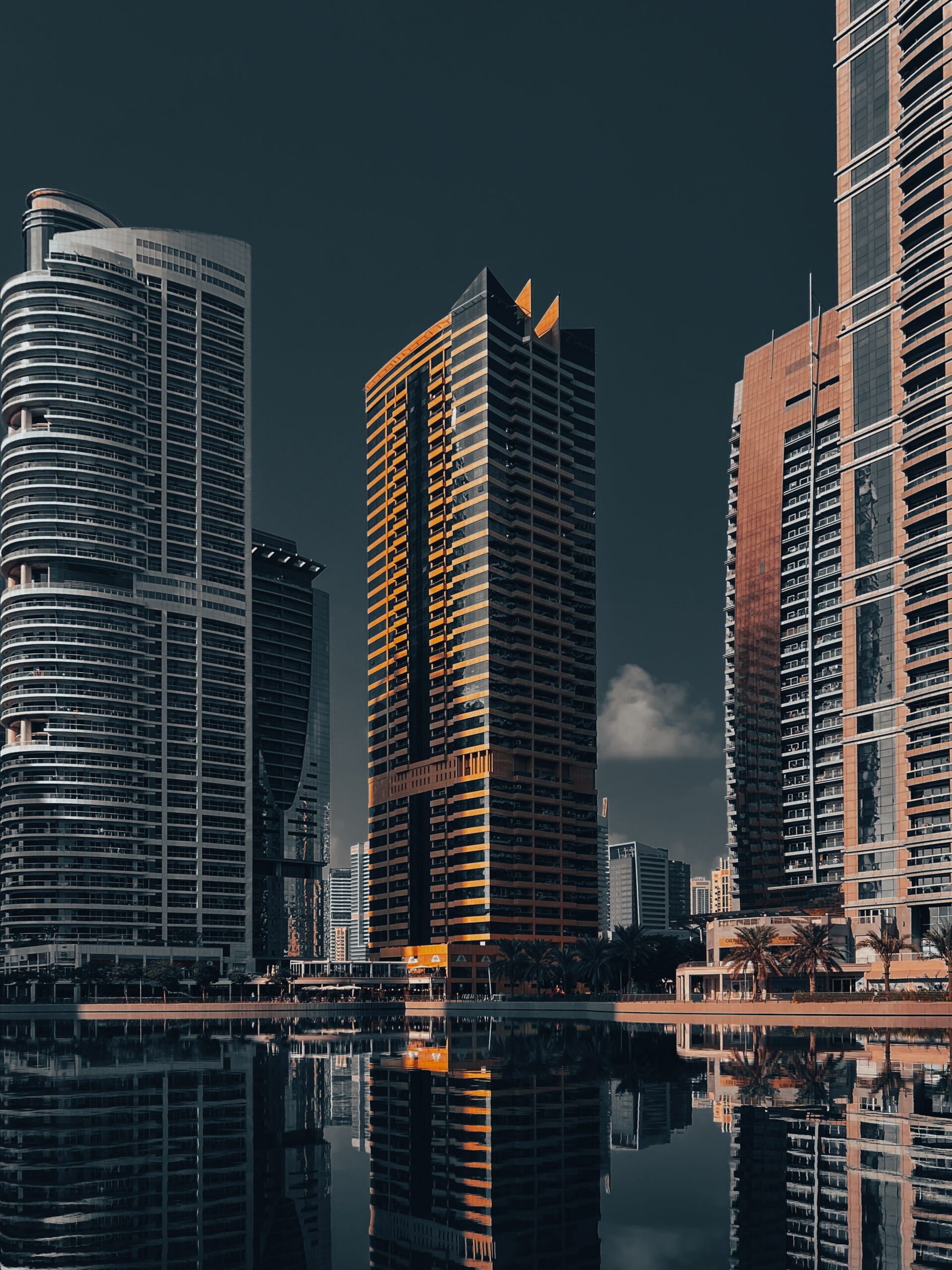 Jumeirah Lake Towers skyscrapers at dusk with orange-lit facades reflecting in the lake, representative of Lake Side Residence in JLT Cluster A