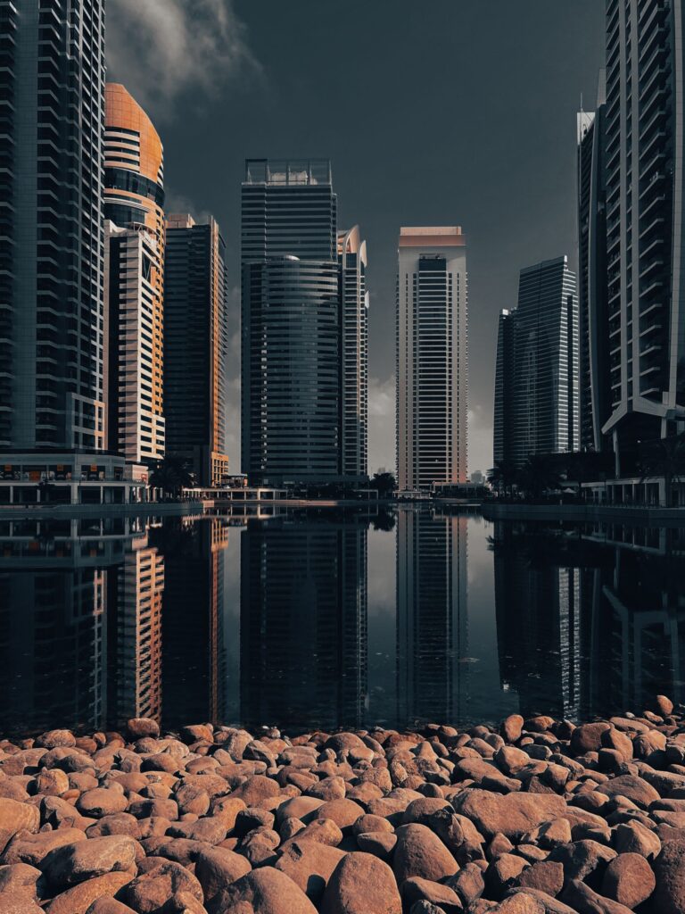 Moody Jumeirah Lake Towers reflection with rocky foreground, no people, no legible branding